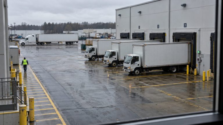 A wet loading yard with box trucks parked at warehouse dock doors